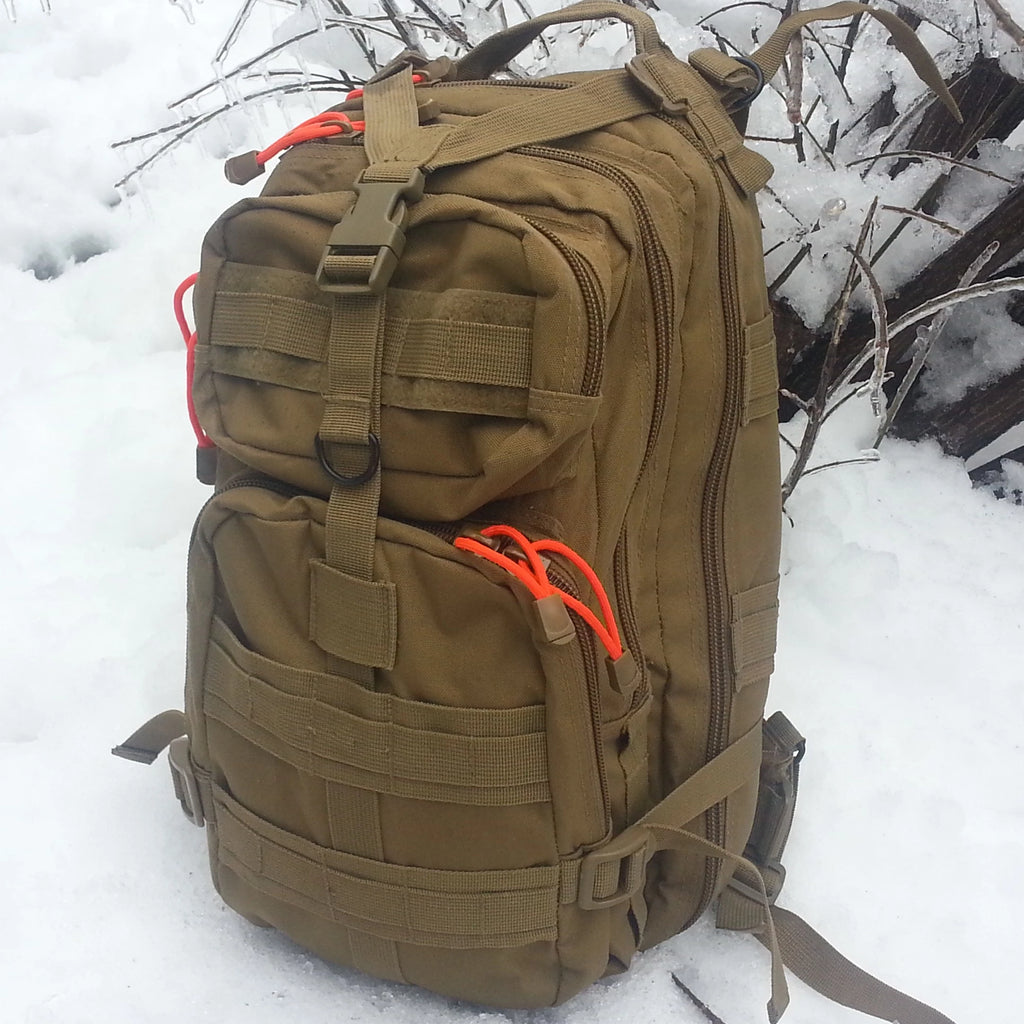 Brown tactical backpack with orange straps on a snowy background