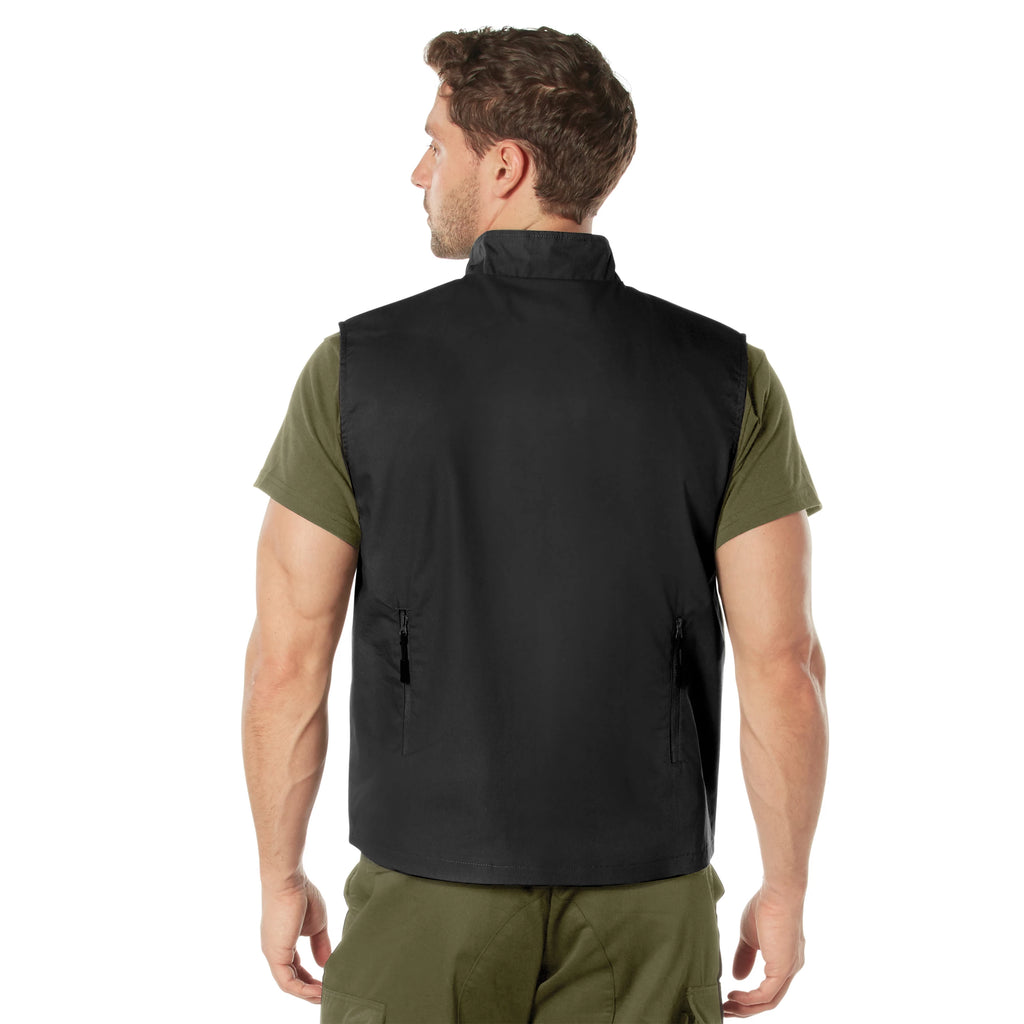 Man wearing a black vest over an olive green shirt and pants on a white background