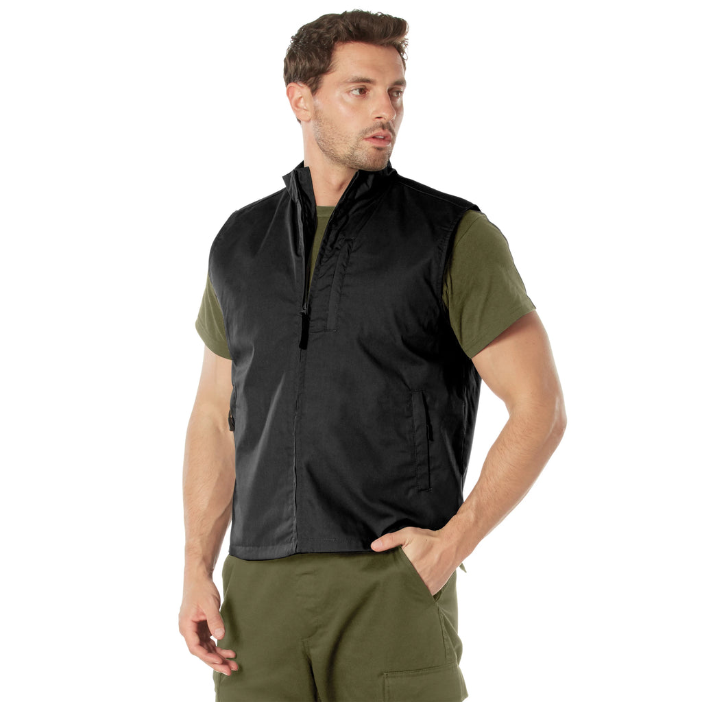 Man wearing a black vest over a green shirt and pants on a white background