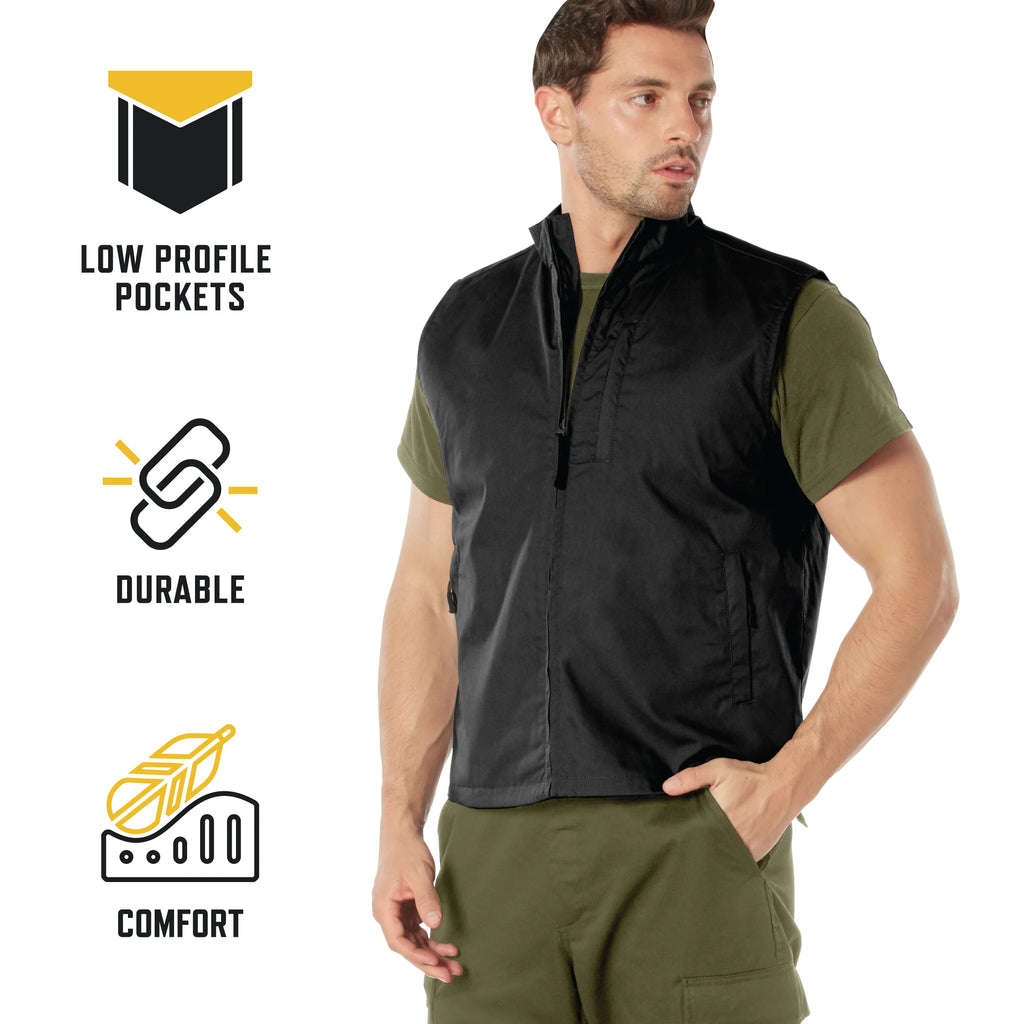 A man wearing a black sleeveless zip-front vest over an olive green shirt and matching green pants, standing against a white background with three feature callouts on the left: low profile pockets, durable construction, and comfort.